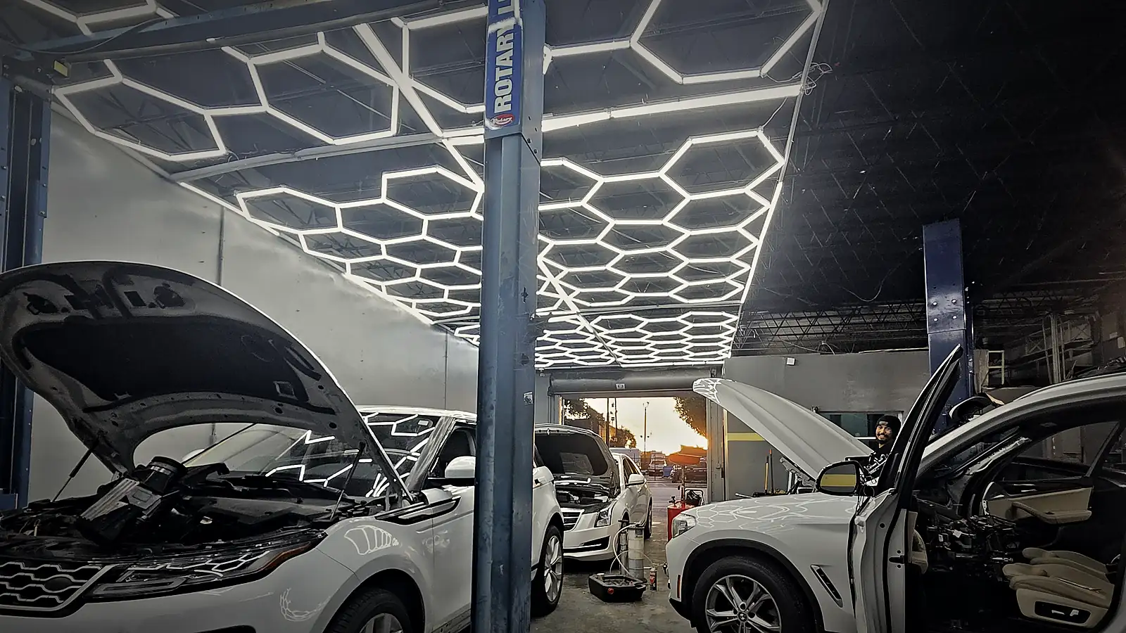Range Rover Evoque and BMW X3 in a Prestige service bay under a hexagon-light ceiling