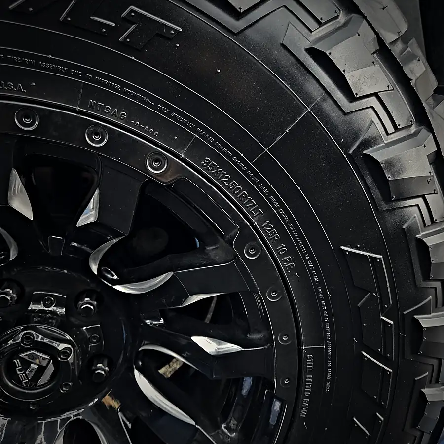 Close-up of a large off-road tire on a black wheel in the shop